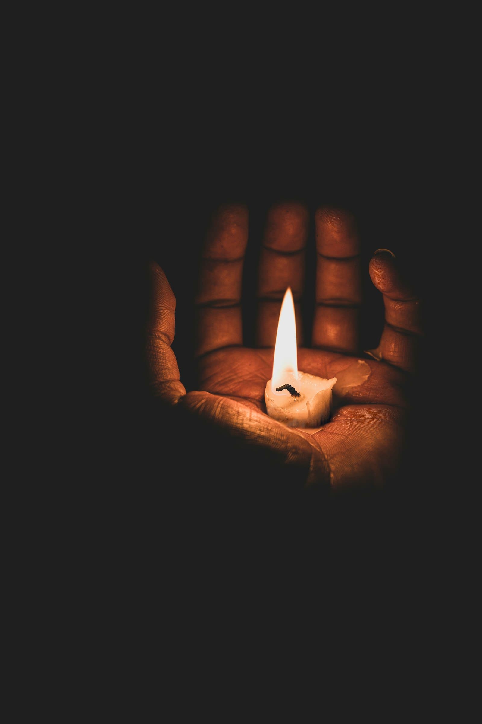 A lit candle held in cupped hands